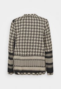 Camicia a maniche lunghe con motivo a gambretto in nero e beige, con strisce orizzontali e dettagli testurizzati sull'orlo.