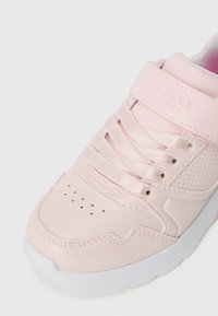 Sneaker rosa chiaro con tomaia sintetica liscia, punta tonda, dettagli perforati e chiusura con lacci. Presenta una fascia in Velcro.