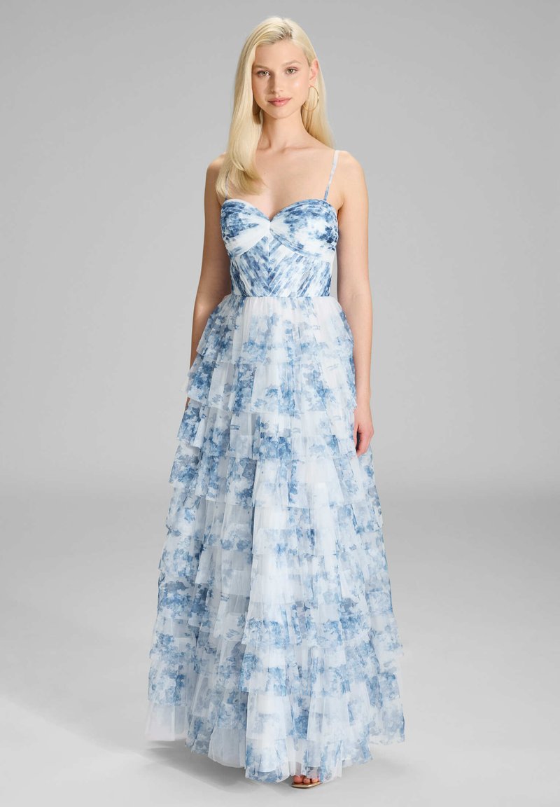 Robe maxi en tissu tie-dye bleu et blanc avec une texture superposée à volants. Bretelles spaghetti et décolleté en cœur. Élégante fluidité.