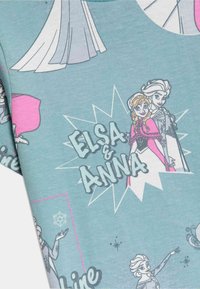 Tela azul clara con personajes impresos de Elsa y Anna. Presenta acentos coloridos, burbujas de diálogo y motivos de copos de nieve.