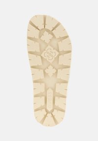 Sole della scarpa color crema con una suola testurizzata caratterizzata da motivi a diamante e geometrici. Logo impresso nella sezione centrale.