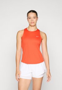 Rød atletisk tanktop med rund hals, lavet af glat stof. Har et lille hvidt logo på brystet og er i kombination med hvide shorts.