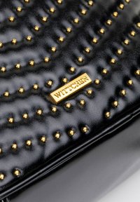 Czarna skórzana torebka o teksturowanej powierzchni, z złotymi ćwiekami i wyraźnie widoczną złotą plakietką z logo WITTCHEN.