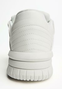 White sneaker with a smooth leather upper, quilted design on the back, padded collar, and textured rubber outsole.