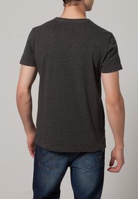 Camiseta de manga corta color gris carbón con cuello redondo. Fabricada con una tela suave, de textura lisa, presenta un dobladillo recto y un diseño minimalista.