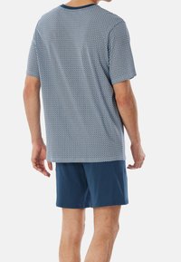 Blue and white short-sleeve shirt with a geometric pattern, paired with solid navy shorts. Cotton material, casual fit, and crew neckline.
