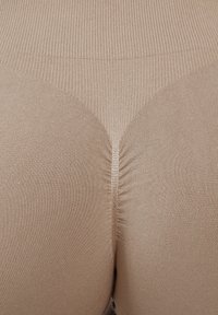 Leggings seamless alta vita in tonalità tan, con texture a coste, vestibilità aderente e dettaglio di cucitura arricciata sul retro per un effetto contouring.