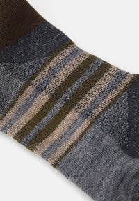 Ullstrumpor med ett flerfärgat randigt mönster i marinblått, olivgrönt och beige. Texturerad stickad tyg med förstärkt tåområde.