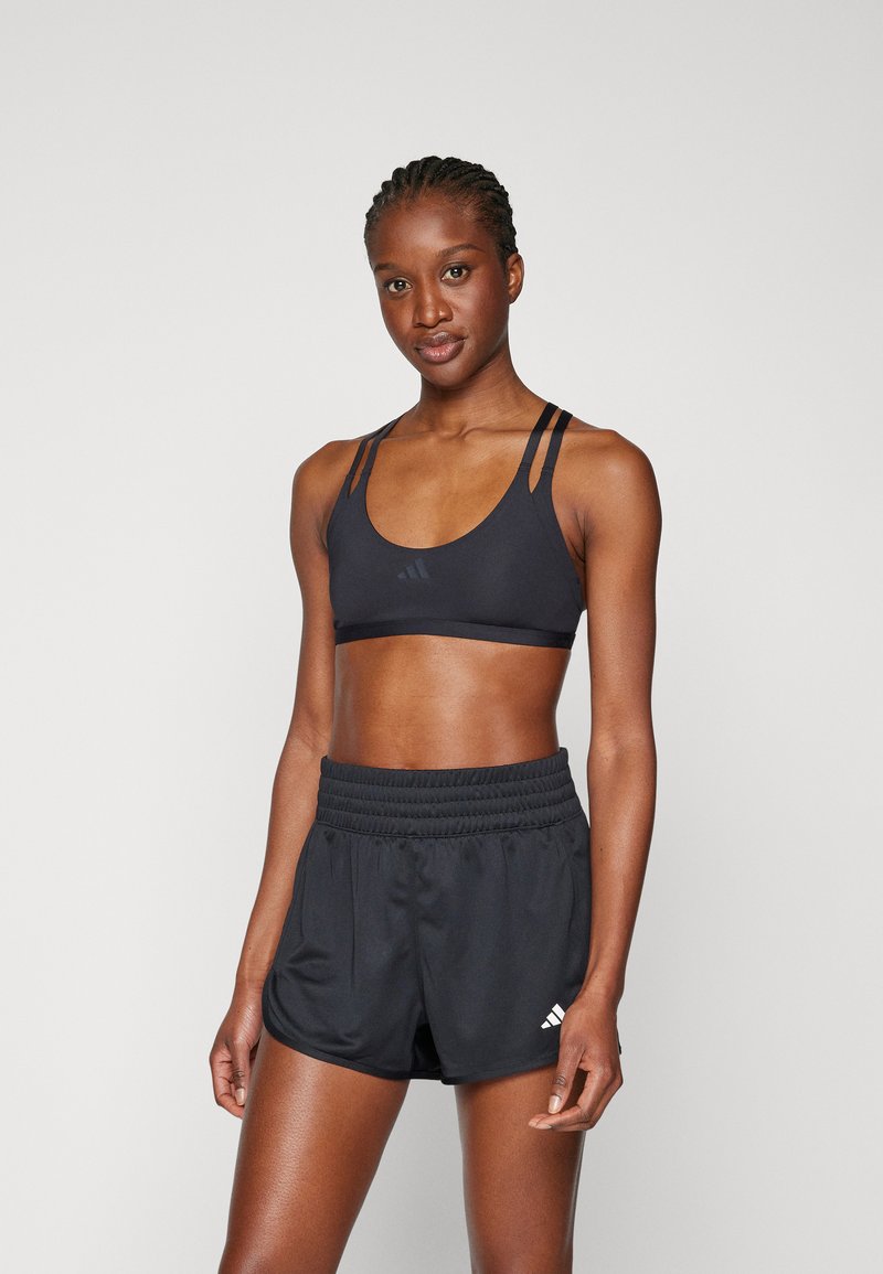 Zwarte sportbeha met verstelbare bandjes, logo op de voorkant; gecombineerd met zwarte shorts met een elastische tailleband en logofinalen.