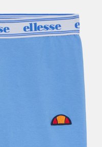 Shorts bleu clair avec une texture douce, dotés d'une taille élastique avec le logo "ellesse" et un petit logo brodé en rouge et orange.