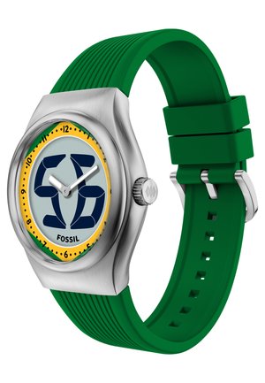 Montre analogique avec bracelet en silicone vert, boîtier argenté, cadran jaune et vert avec chiffres noirs et aiguilles blanches des heures et des minutes.