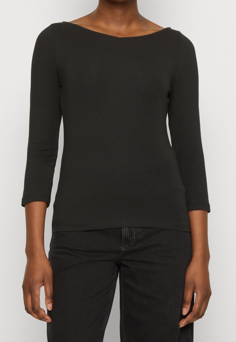 Svart, figurnära långärmad topp med båtformad halsringning. Tillverkad av ett slätt material, har trekvartsärmar och en enkel, ren design.