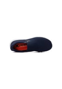 Zapatilla marinera sin cordones con una parte superior texturizada y tela elástica. La suela blanca presenta patrones de tracción. El interior tiene un forro rojo con la marca.