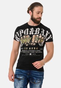 Schwarzes Baumwoll-T-Shirt mit auffälligem Grafikdruck, der den Text "Geld ist König" und ein Knöchelmuster zeigt. Rundhalsausschnitt, kurze Ärmel, enganliegender Schnitt.