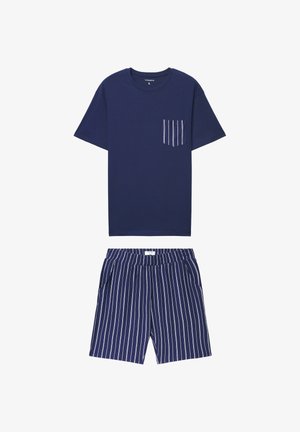 T-shirt in cotone blu navy con taschino sul petto a sottili righe bianche, abbinata a pantaloncini blu navy con righe bianche verticali.