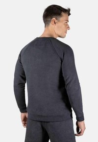 Mørkegrå crewneck sweatshirtt med raglanermer, ribbede mansjetter og hem. Myk tekstur, minimalistisk design, med en liten etikett på ryggen.