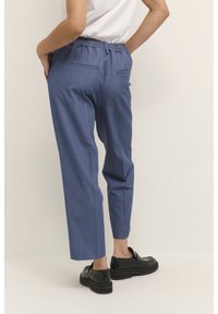 Blå, lätta byxor med avslappnad passform, elastisk midja och två bakfickor. Kombineras med blanka svarta loafers för kontrast.