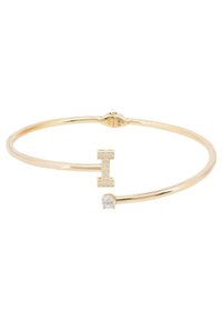 Pulsera bangle en tono dorado con un acento en forma de letra "I" adornado con piedras transparentes y un detalle de piedra redonda y clara, textura de metal suave.