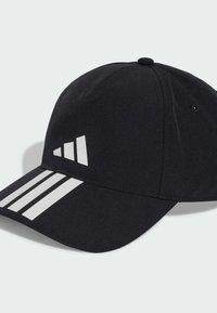 Gorra de béisbol negra hecha de tela suave. Presenta tres rayas blancas en la visera y un logo triangular distintivo en la parte frontal.