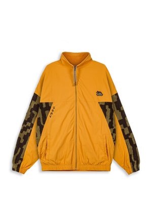 Chaqueta amarilla con cremallera y cuello alto, con mangas de patrón de camuflaje marrón, bolsillos laterales y un pequeño logo en el pecho. Tejido texturizado.