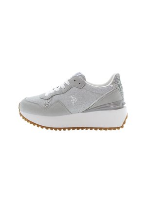 Zapatilla deportiva femenina gris con cordones blancos, suela blanca gruesa, acento de brillo en el talón y parte superior texturizada con un pequeño logo en el lateral.