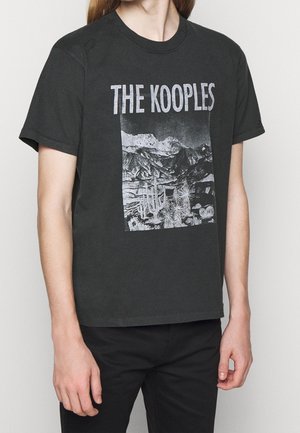 Czarna koszulka z krótkim rękawem z białym napisem „THE KOOPLES” i grafiką w odcieniach szarości przedstawiającą góry i kaktusy z przodu.