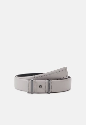 Ceinture en cuir gris clair roulée avec boucle métallique noire gravée du logo Calvin Klein, coutures visibles le long des bords.