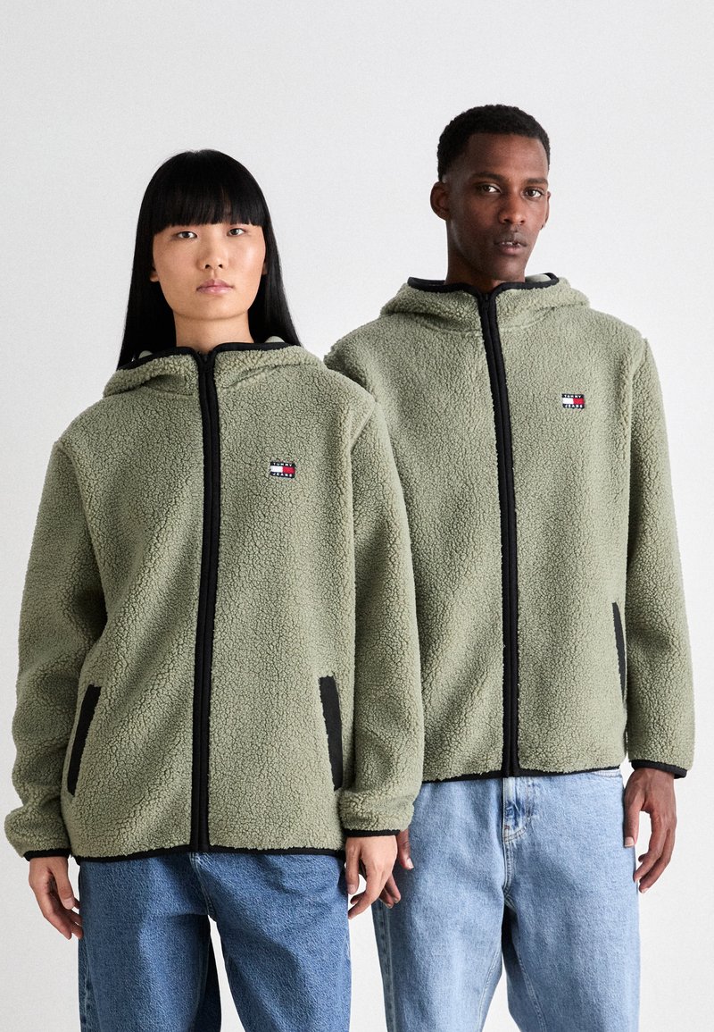 Fleece jack in olijfgroen, met een capuchon, zwarte ritssluiting en zijzakken met een logo op de borst. Relaxte pasvorm.