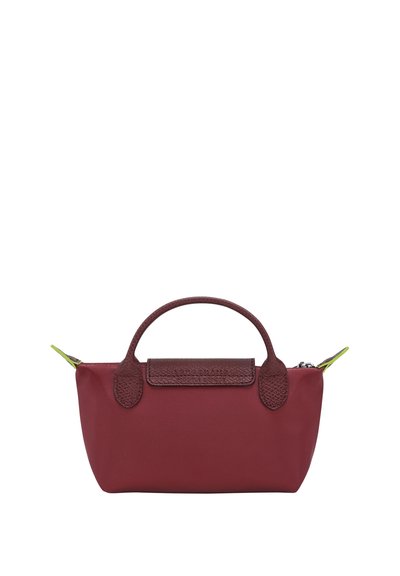 Rote Stofftasche mit Lederakzenten, runden Griffen und einem Reißverschluss. Mit einem kontrastierenden grünen Reißverschlussanhänger.