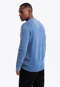 Suéter de punto azul claro con mangas largas, puños y dobladillo acanalados, y cuello redondo; la textura parece suave y lisa.