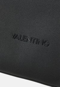 Czarny skórzany portfel o teksturowanej powierzchni z wytłoczonym logo "Valentino", prezentujący gładkie wykończenie i subtelną strukturę.