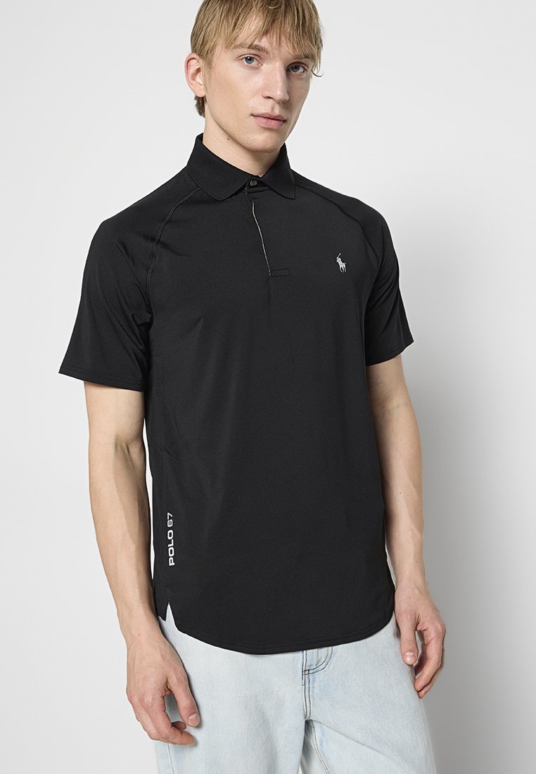 Schwarzes Kurzarm-Polohemd mit kragenlosem Ausschnitt, das dezente Seitenschlitze und ein kleines gesticktes Logo auf der linken Brust aufweist.