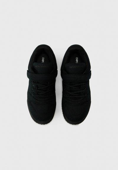 Black sneakers with a textured fabric upper, round toe, lace-up design, rubber sole, and prominent branding on the tongue.