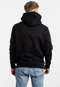Felpa nera con cappuccio e tasca a marsupio, in morbido tessuto, con polsini e orlo a coste; indossata con jeans blu chiaro, mostrando una vista posteriore casual.