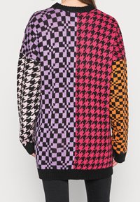 Strickpullover mit Schachbrettmuster in Lila, Rot, Schwarz und Orange. Lange Ärmel, Rundhalsausschnitt sowie gerippte Bündchen und Saum.