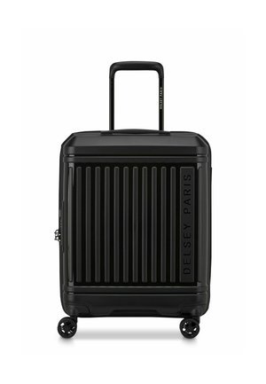 Valise rigide noire avec des rainures verticales, dotée d'une poignée télescopique et de double roulettes pivotantes. Marquée "DELSY PARIS" sur le côté.