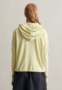 Lichtgele hoodie met een relaxte pasvorm, lange mouwen en een trekkoordkap. Zachte stof met een geribbeld textuur en een iets verkorte zoom.