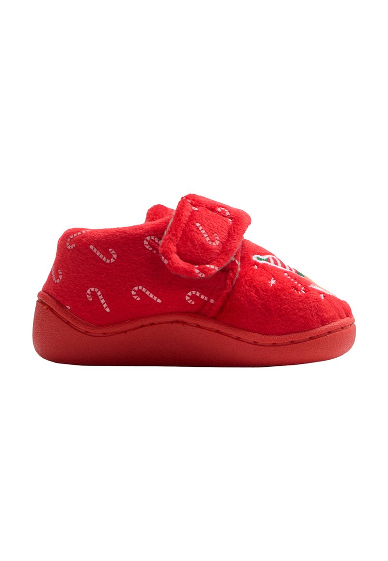 Zapatilla de forro polar roja con una tira de velcro, con un patrón de bastón de caramelo y suela de goma roja lisa. Diseño de corte bajo para facilitar el calzado.