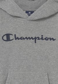 Felpa grigia con cappuccio realizzata in morbido tessuto, caratterizzata da un grande logo blu navy con la scritta "Champion". Include una tasca frontale e polsini a coste.