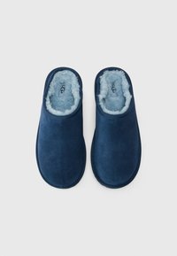 Chaussons en daim bleu marine avec une douce doublure en fourrure bleu clair, design à enfiler et bout rond. Présente des coutures renforcées autour des bords.