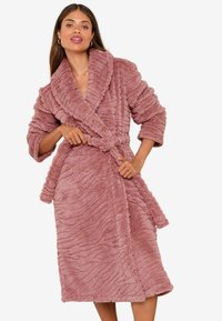Accappatoio rosa fuzzy con un motivo a onda testurizzato, colletto sciallato, maniche oversize e vita con cintura. Tessuto morbido e peluche in tutto.