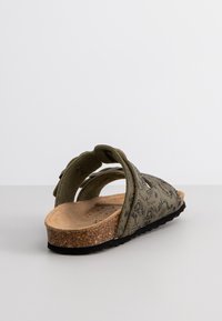 Sandalia verde con patrón, con tiras anchas, plantilla de corcho y suela exterior negra. Presenta recortes en las tiras para ventilación.