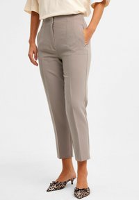 Harmaat muotonsa mukaiset housut, joissa on vetoketjukiinnitys ja sivutaskut, joissa on kapeampi malli ja lyhyt pituus. Yhdistetty leopardikuvioisiin korkokenkiin.