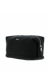 Trousse de toilette en cuir noir avec surface texturée, fermeture éclair argentée et logo embossé. Forme rectangulaire avec bords légèrement arrondis.