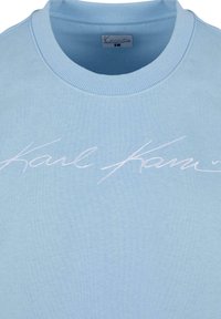 Sweatshirt bleu clair en tissu doux. Doté d'un col rond côtelé et d'une signature brodée "Karl..." en blanc sur le devant.