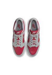 Sneaker Nike con una combinazione di colori grigia e rossa, parte superiore in pelle, punta tonda, dettagli perforati e lacci piatti.