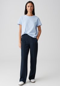Lichtblauw katoenen t-shirt met opgerolde mouwen, gecombineerd met marineblauwe wijde broek met een soepele textuur en voorplooien.
