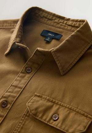 Brown button-up shirt made of textured fabric, featuring a collar, front pocket, and two brown buttons. Brand label visible inside collar.