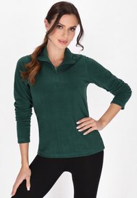 Pull en polaire vert avec un col zippé, des manches longues et une texture douce. Conçu pour un ajustement décontracté avec un ourlet arrondi.