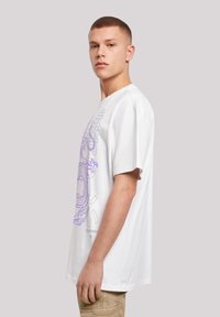 White cotton t-shirt featuring a purple graphic design on the front. Relaxed fit with short sleeves and a crew neckline.